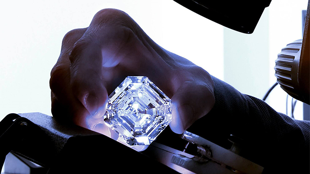 Close-up of scientist’s hand holding the 302-carat Lesedi La Rona diamond under the light of a microscope