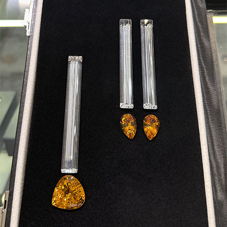 Figure 11. Elongated baguette-cut rock quartz from Brazil (left, 80 × 10 mm, 61.41 ct stone; right, two 70 × 9 mm stones totaling 83.07 carats) accented by Bolivian citrine (left, 25.27 ct triangular brilliant; right, two pear brilliants totaling 15.30 carats). Photo by Jennifer Stone-Sundberg; courtesy of Pillar & Stone International.