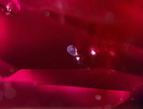Figure 2. Heat-altered crystal inclusions surrounded by a discoid fracture, proving that the spinel underwent high-temperature treatment. Photomicrograph by Tsz Wing Lai; field of view 2.40 mm. Figure 2. Heat-altered crystal inclusions surrounded by a discoid fracture, proving that the spinel underwent high-temperature treatment. Photomicrograph by Tsz Wing Lai; field of view 2.40 mm.