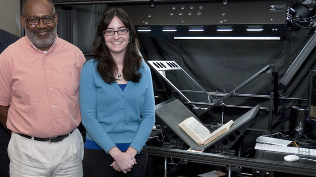 Two research librarians stand in front of the high-tech book scanner.