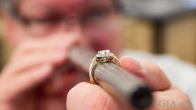 A man holds a long round metal rounded column of metal with a ring on it. The ring is in focus, his face in the background is not.