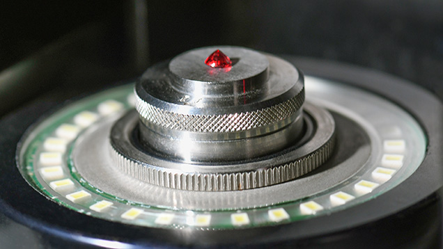 Figure 1. A red gemstone set table-down in a noncontact optical measurement device. Photo by Annie Haynes. Figure 1. A red gemstone set table-down in a noncontact optical measurement device. Photo by Annie Haynes.