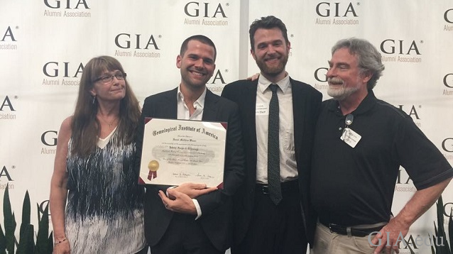 group of four people (mom, two sons and dad) stand in front of GIA backscreen with one son holding GIA diploma. group of four people (mom, two sons and dad) stand in front of GIA backscreen with one son holding GIA diploma.