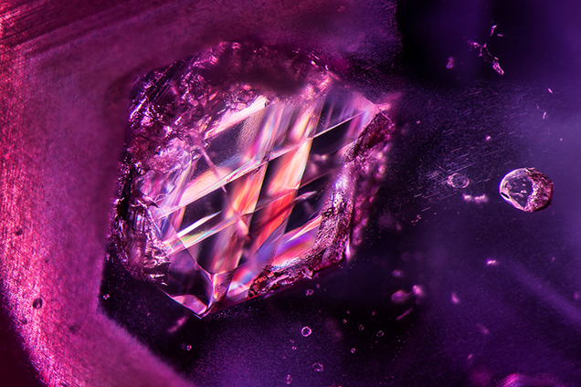 Viewed between crossed polarizers, an included calcite crystal within an unheated Burmese ruby displays dramatic twinning planes. Photomicrograph by E. Billie Hughes; field of view 3.90 mm.