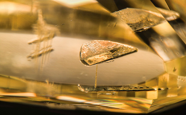 Laboratory-grown diamond contains a flux inclusion and laser drill holes.