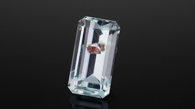 Red garnet crystal prominently featured in the faceted aquamarine.