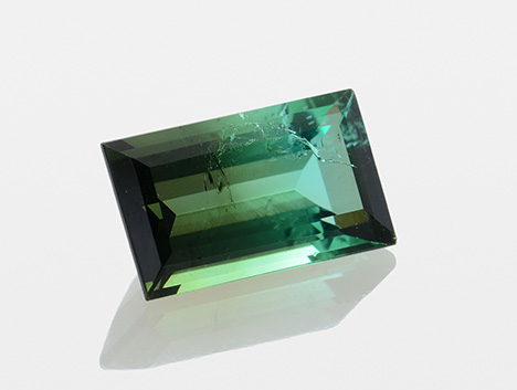 A bicolor tourmaline displays bluish green to dark yellowish green bodycolor.