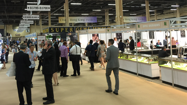 留步在展会大厅的一条过道中聊天的人们。 其他人漫步闲逛各个展位并鉴赏商品。