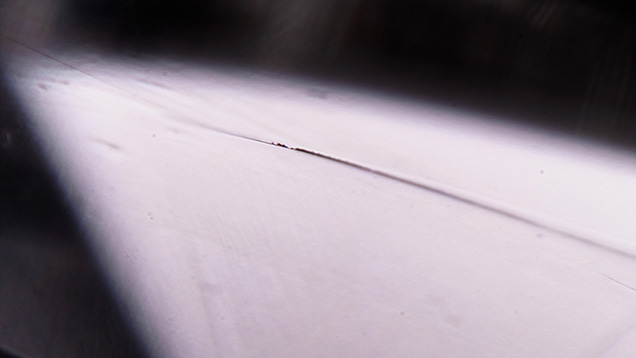 Figure 2. Dark residue is visible in some parts of the channel, as seen through the pavilion. The appearance of the residue is similar to that of graphitized carbon but could also be attributed to non-diamond carbon. Photomicrograph by Elina Myagkaya; field of view 1.99 mm.