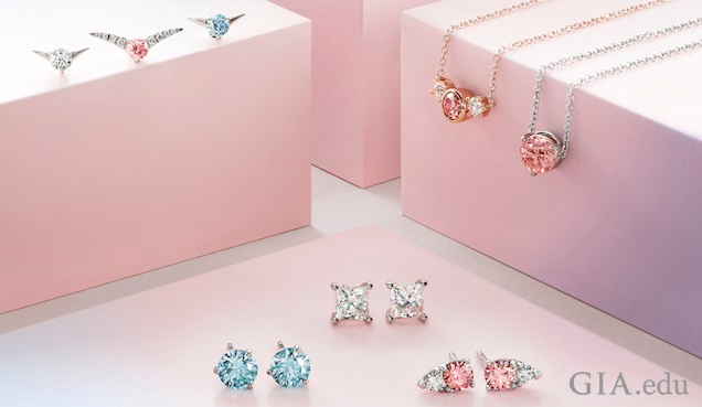 Clear, blue and pink synthetic diamond jewelry is displayed around and on pink boxes.