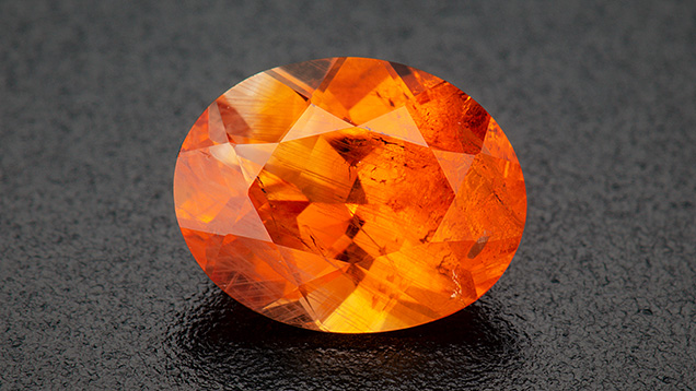 Figure 2. A 0.89 ct heated orange oval brilliant sapphire. Photo by Robert Weldon; courtesy of Greenland Ruby.