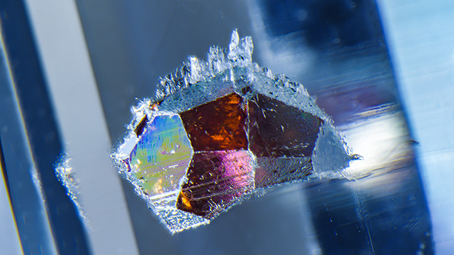 Vibrant interference colors seen on the crystal faces of the garnet.