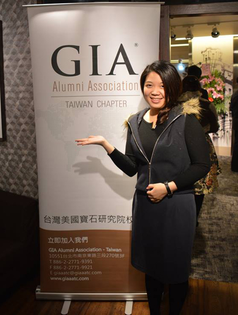 活动现场一位站在 GIA 旗帜前的女士。