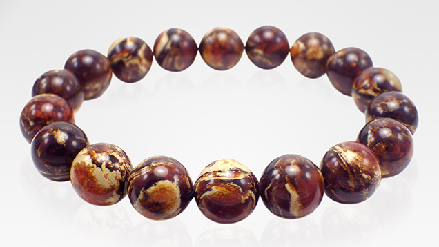Dark brown “root amber” beads exhibit light yellow creamy swirls. Dark brown “root amber” beads exhibit light yellow creamy swirls.