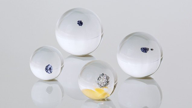 Figure 1. Weighing between 3.07 and 10.53 ct, these four small transparent colorless spheres of rock crystal quartz each hosted an opaque black inclusion (one sphere contained two inclusions). Photo by Annie Haynes.