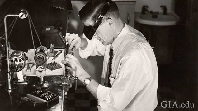 A man works at a jeweler’s bench.