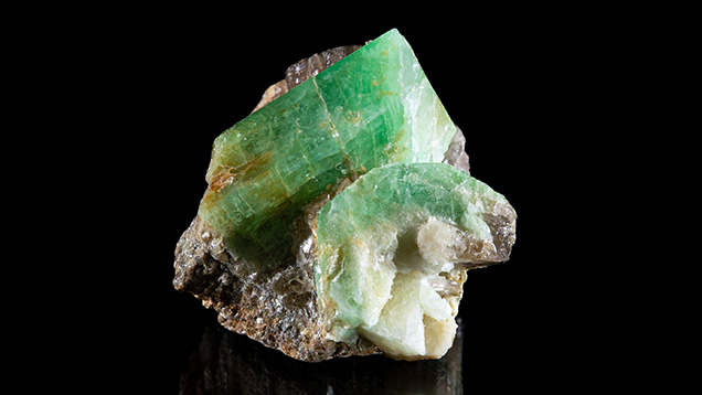 Figure 2. In situ emerald and beryl from Newfoundland. The primary crystal shows a lively green hue. The crystal on the lower right shows strong concentric zonation with a green rim and a white core. Photo by Emma Hutchinson Photography; courtesy of Art Gardner.