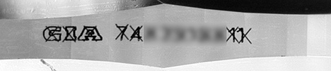 Figure 2. GIA’s standard procedure is to cross out the counterfeit inscription. Image by GIA staff.