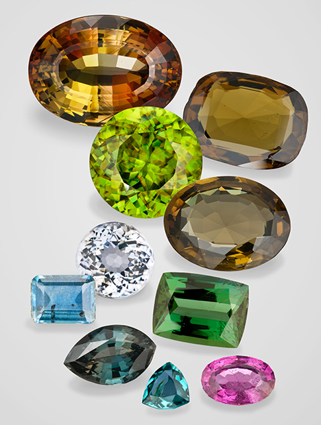 Figure 4. Alluvial gems that are less often found loose in sediments. From left to right and top to bottom: 14.41 ct andalusite, Brazil; 18.50 ct sinhalite, Sri Lanka; 13.00 ct sphene, Madagascar; 11.19 ct kornerupine, Sri Lanka; 2.62 ct sillimanite, Sri Lanka; 3.20 ct zoisite, Tanzania; 2.77 ct kyanite, Madagascar; 1.68 ct sapphirine, Sri Lanka; 0.29 ct grandidierite, Sri Lanka; and 1.23 ct taaffeite, Sri Lanka. Composite image by Robert Weldon.