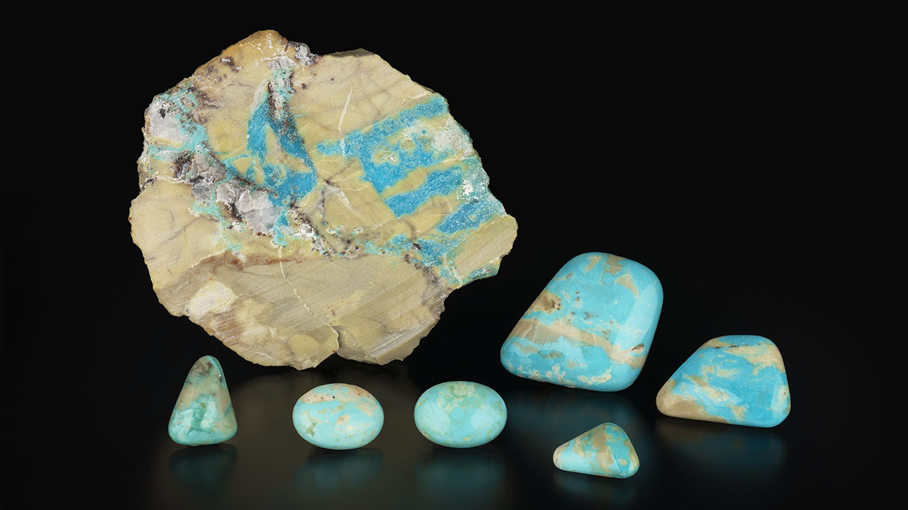 Figure 11. Stabilized turquoise cabochons (ML-01 through ML-06) weighing 4.16–37.19 ct and a 57.9 g slab from the Mona Lisa mine. Photo by Emily Lane; courtesy of Avant Mining LLC.
