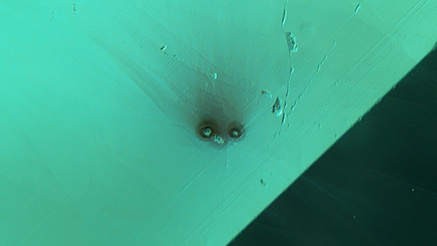 Figure 2. Top view of an altered etch tube in tourmaline resembling the face of a bird with a fuzzy tuft. Photomicrograph by Jamie Price; field of view 1.48 mm.