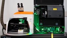 The green light produced by the laser is focused by the optical components of the instrument so it is aligned along the light path in the binocular microscope. By observing the sample with the microscope, the researcher can collect Raman spectra not only for the gem sample, but for mineral inclusions within the sample in order to identify them. 