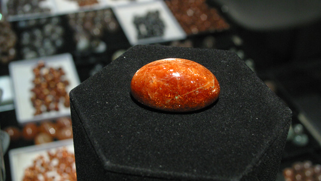 The unusual size of this 146.07-ct. oligoclase sunstone dwarfs the sunstones, moonstones, and other gems in the background. – Terri Weimer, courtesy Blue Moon Enterprise