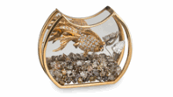 A crescent-shaped bowl with a flat bottom trimmed in gold holds rough diamond gravel and a gold and diamond fish.